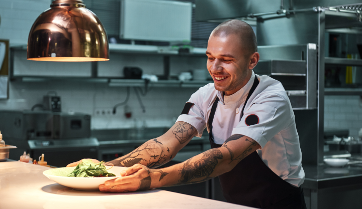 young male chef smiling at plate of lettuce