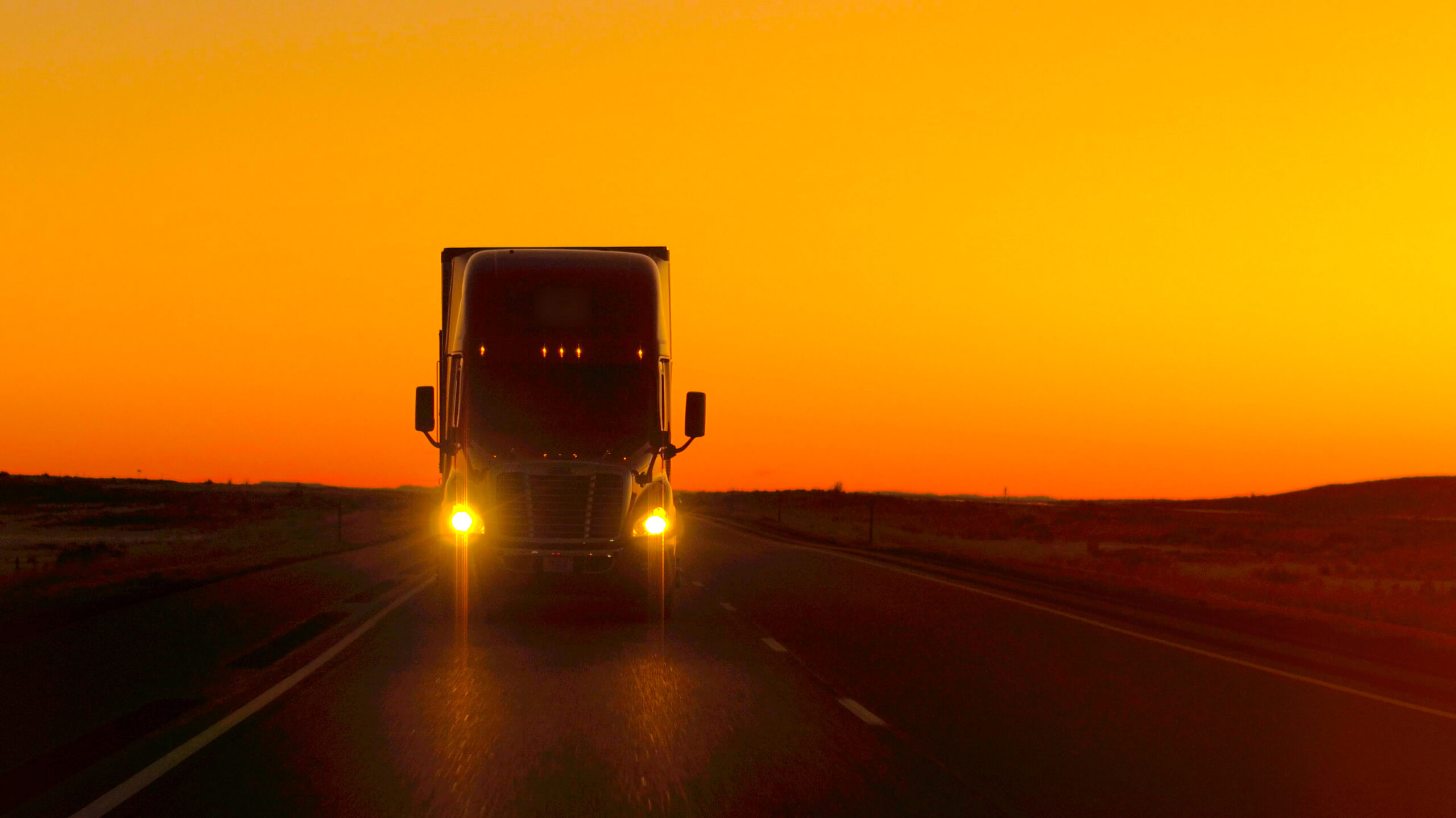 truck driving on road in front of sunset