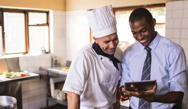 men laughing at tablet in kitchen