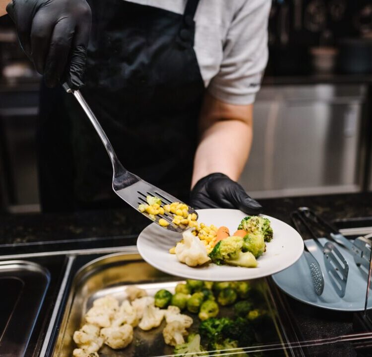 person serving vegetables on plate